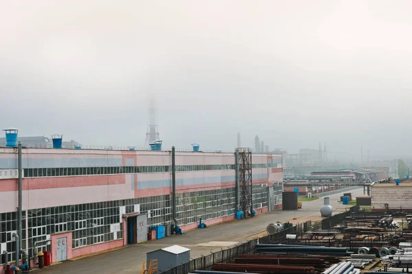 Endüstriyel manzara. Panoramik teknolojik borular. Paslı boruları, mavi yakut, üretim iletişim. Üretim binalar tamir. Puslu bir gökyüzü arka planı