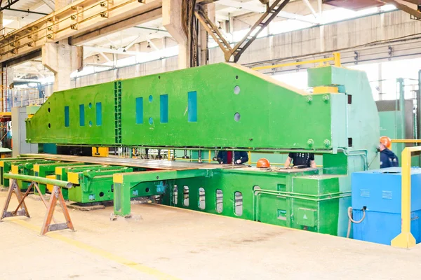 Industrial production equipment for metal processing. The device is large and heavy green. With a line for the reception and transmission of spare parts, conveyor. At the chemical plant