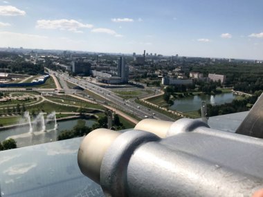Profilde beyaz-mavi gökyüzü karşı görüş bozuk para sabit dürbün. Bir yükseklikte görüntüleme platformu üzerinde gri metal dürbün. Güzel yeşil şehir manzaralı çatı