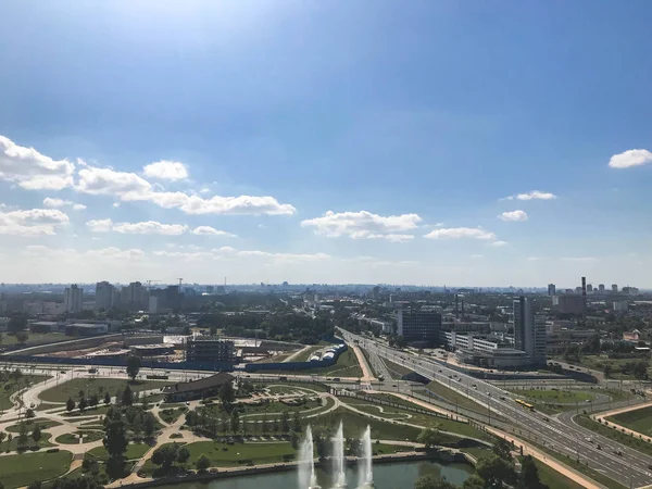 Panoramatický pohled z velké výšky na krásné zelené město s mnoha silnic a výškových budov. Pohled na město z ochozu z výšky. Níže jsou fontány a šťastní lidé — Stock fotografie