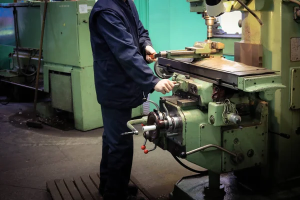 Un trabajador masculino trabaja en un torno de cerrajero de hierro metálico más grande, equipo para reparaciones, trabajos de metal en un taller en una planta metalúrgica en una producción de reparación — Foto de Stock