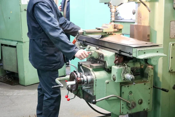 Un operaio di sesso maschile lavora su un grande tornio metallurgico per fabbri, attrezzature per le riparazioni, lavorazione dei metalli in un'officina in un impianto metallurgico in una produzione di riparazione — Foto Stock