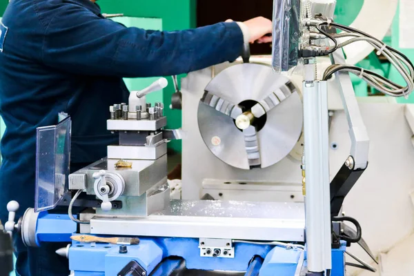 A male worker works on a larger metal iron locksmith lathe, equipment for repairs, metal work in a workshop at a metallurgical plant in a repair production — Stock Photo, Image