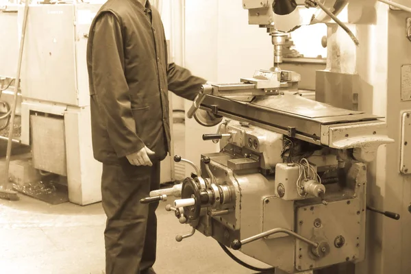 Un trabajador masculino trabaja en un torno de cerrajero de hierro metálico más grande, equipo para reparaciones, trabajos de metal en un taller en una planta metalúrgica en una producción de reparación — Foto de Stock