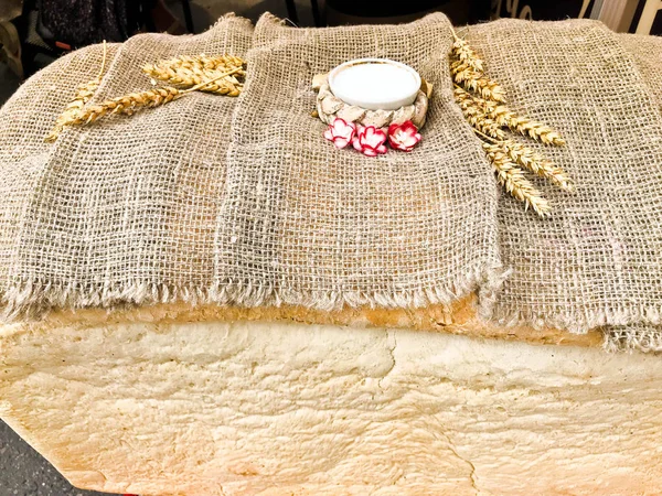 Um grande, enorme pão retangular de pão de trigo caseiro e branco com uma crosta e sal. Tradição russa para conhecer hóspedes. pão feito por mãos femininas — Fotografia de Stock
