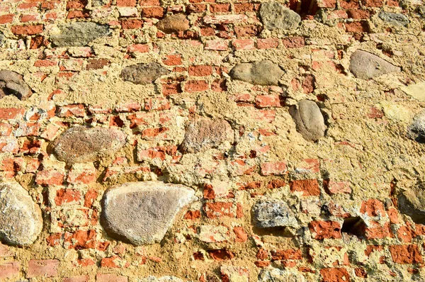 La texture de la vieille pierre antique médiévale dur peeling mur de briques craquelées rectangulaires de briques d'argile rouge et de grandes pierres, pavés. Le contexte — Photo