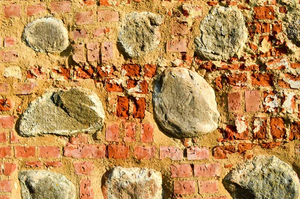 A textura da antiga pedra antiga medieval antiga descascamento duro parede de tijolo rachado de tijolos retangulares de argila vermelha e pedras grandes, pedras de paralelepípedos. O fundo — Fotografia de Stock