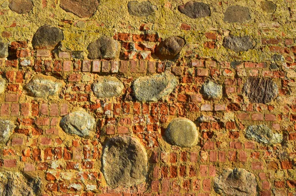 A textura da antiga pedra antiga medieval antiga descascamento duro parede de tijolo rachado de tijolos retangulares de argila vermelha e pedras grandes, pedras de paralelepípedos. O fundo — Fotografia de Stock