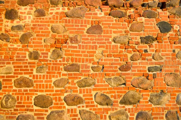 La consistenza della vecchia pietra antica medievale pietra dura peeling incrinato muro di mattoni rettangolari di argilla rossa e grandi pietre, ciottoli. Lo sfondo — Foto Stock