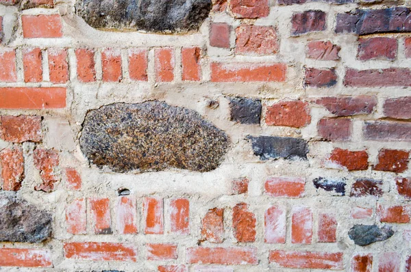 A textura da antiga pedra antiga medieval antiga descascamento duro parede de tijolo rachado de tijolos retangulares de argila vermelha e pedras grandes, pedras de paralelepípedos. O fundo — Fotografia de Stock