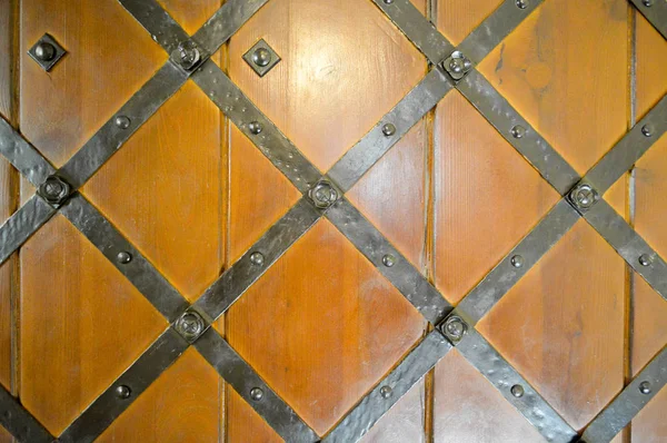Текстура старинных средневековых античных прочных деревянных натуральных толстых дверей с заклепками и узорами ногтей и замками из деревянных досок. Фон — стоковое фото