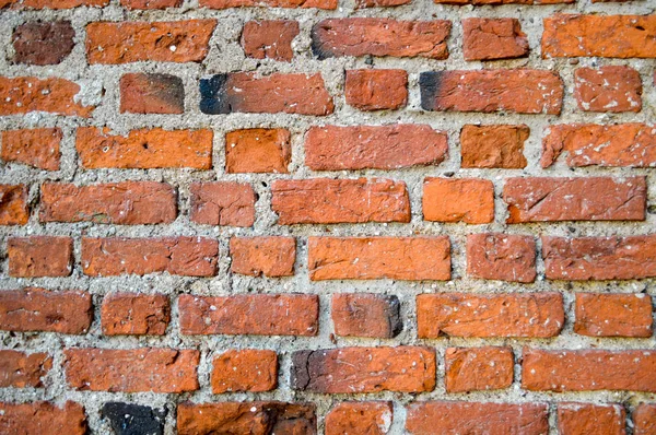 Die Textur der alten mittelalterlichen antiken stabilen Stein abblätternden zerkratzten Wand aus rechteckigen roten orange helle Ziegel mit Nähten und Rissen. der Hintergrund — Stockfoto