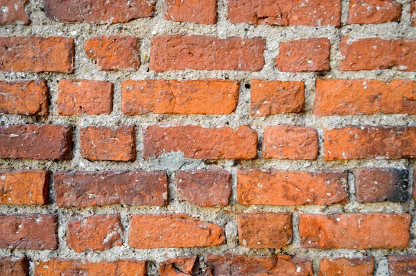 Die Textur der alten mittelalterlichen antiken stabilen Stein abblätternden zerkratzten Wand aus rechteckigen roten orange helle Ziegel mit Nähten und Rissen. der Hintergrund — Stockfoto