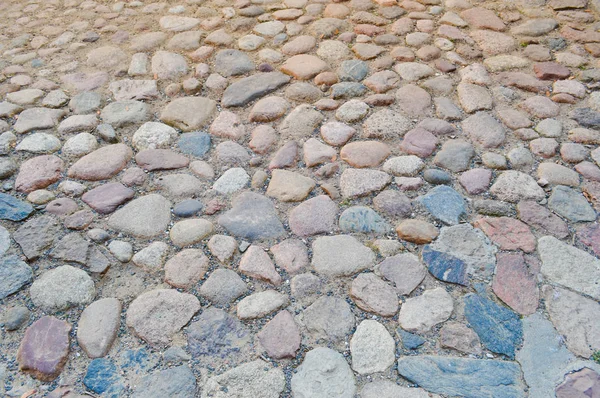 The texture of the stone road, pavement, walls of large gray old medieval round strong stones, cobblestones. The background