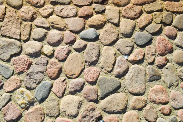 Текстура каменной дороги, тротуар, стены больших серых старинных средневековых круглых сильных камней, булыжники. Фон — стоковое фото