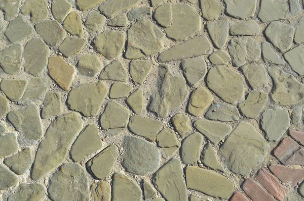 The texture of the stone road, pavement, walls of large gray old medieval round strong stones, cobblestones. The background