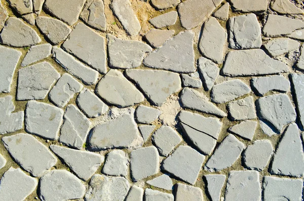 De textuur van de steen weg, stoep, muren van grote grijze oude middeleeuwse ronde sterke stenen, keien. De achtergrond — Stockfoto