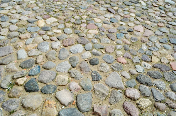 De textuur van de steen weg, stoep, muren van grote grijze oude middeleeuwse ronde sterke stenen, keien. De achtergrond — Stockfoto