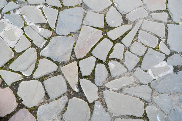 Die Beschaffenheit der Steinstraße, Pflaster, Mauern aus großen grauen alten mittelalterlichen runden starken Steinen, Kopfsteinpflaster. der Hintergrund — Stockfoto