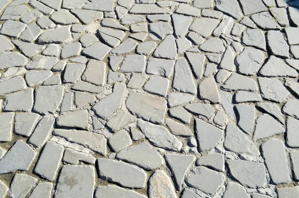 De textuur van de steen weg, stoep, muren van grote grijze oude middeleeuwse ronde sterke stenen, keien. De achtergrond — Stockfoto