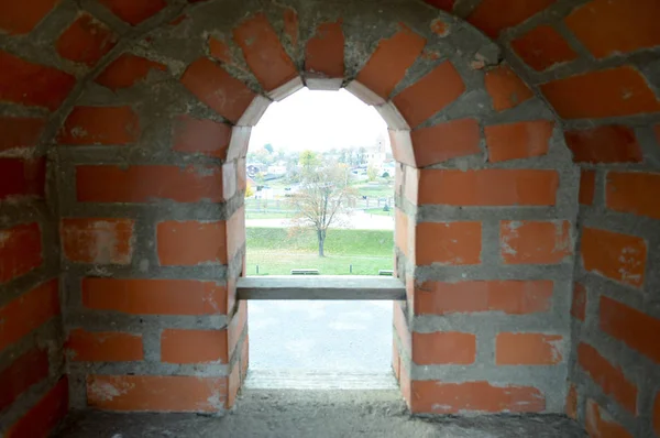 Una piccola finestra stretta su un antico muro di mattoni spessi in pietra in un vecchio castello. Lo sfondo — Foto Stock