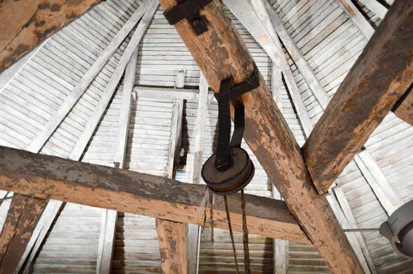La textura de la antigua madera antiguas vigas gruesas y resistentes, retardo y techos y mecanismo de elevación de carga, ruedas, polipastos bajo el techo. El trasfondo — Foto de Stock