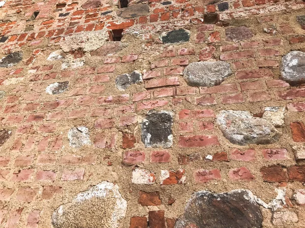 La consistenza della vecchia pietra antica medievale pietra dura peeling incrinato muro di mattoni rettangolari di argilla rossa e grandi pietre, ciottoli. Lo sfondo — Foto Stock