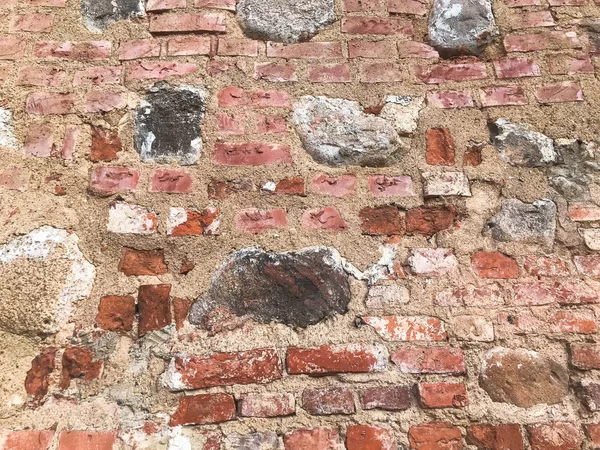 Die Textur der alten mittelalterlichen antiken Stein hart schält rissige Ziegelwand aus rechteckigen roten Lehmziegeln und großen Steinen, Kopfsteinpflaster. der Hintergrund — Stockfoto