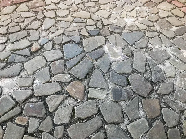 The texture of the stone road, pavement, walls of large gray old medieval round strong stones, cobblestones. The background