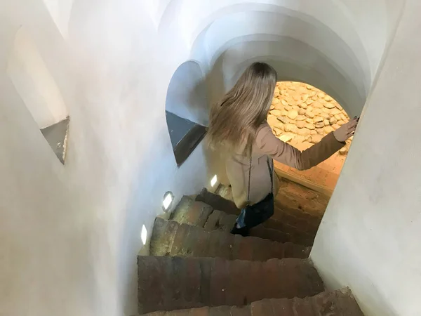 Egy lány, egy nő ereszkedik a meredek kő csigalépcsőn megy le a keskeny lépcsőn — Stock Fotó