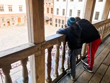 Küçük çocuklar, çocuklar bir ahşap eski balkonda durmak ve demiryoluna eğilerek Şehir Meydanı bakmak