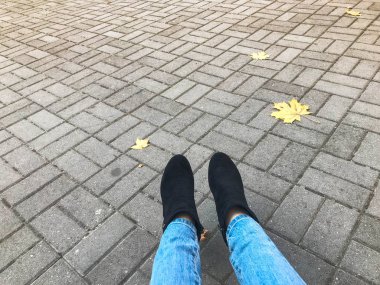 Kot pantolon ve bot, Ayakkabı bir arka plan gri taş beton parke döşeme ve sonbahar sarı yapraklar kadın ince bacaklar. Arka plan