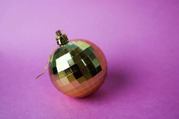 Oro amarillo pequeño vidrio redondo plástico invierno inteligente brillante decorativo hermosa Navidad festiva bola de Navidad, juguete de Navidad pegado con lentejuelas sobre un fondo rosa violeta —  Fotos de Stock