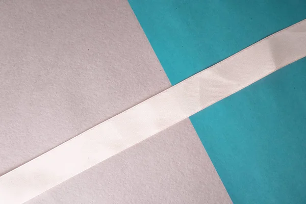 Текстура красивой современной бумаги голубого цвета с розовой лентой из нежной белой ткани модно гламурна. Фон — стоковое фото