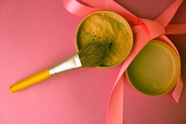 Beauty box, spröda Matt mineralpuder med en brun vackra trä borste från naturliga nap för en make-up på rosa lila bakgrund med en delikat sidenband. Platt låg. Ovanifrån — Stockfoto