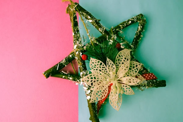 Grande decorativa hermosa estrella de Navidad de madera, una corona de adviento hecho a sí mismo de ramas de abeto y palos en el festivo año nuevo feliz fondo alegre azul-rosa. Decoraciones navideñas — Foto de Stock