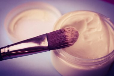 Bir güzellik kutusu ahşap bir fırça ile doğal zor tüysüz bir sesi ve yuvarlak bir kavanoz krem, mavi bir arka plan üzerinde ikinci bir cilt efektli makyaj Bankası için yapılmış. Düz yatıyordu. Üstten görünüm