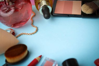 Çerçeve bir ruj, vurgulayıcı, dudaklar, fırça, fırçalar, parfüm, pudra, için bir kalem kadın kozmetik bir dizi mavi bir arka plan üzerinde süsler. Güzellik kutusunu düz yatıyordu. Üstten görünüm