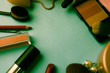 Çerçeve bir ruj, vurgulayıcı, dudaklar, fırça, fırçalar, parfüm, pudra, için bir kalem kadın kozmetik bir dizi mavi bir arka plan üzerinde süsler. Güzellik kutusunu düz yatıyordu. Üstten görünüm