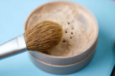 Güzellik kutusu, ufalanan mat mineral toz bir fırçayla özel kahverengi güzel ahşap doğal nap sıcak mavi arka plan üzerinde makyaj için gelen