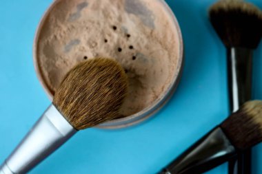 Güzellik kutusu, ufalanan mat mineral toz bir fırçayla özel kahverengi güzel ahşap doğal nap sıcak mavi arka plan üzerinde makyaj için gelen