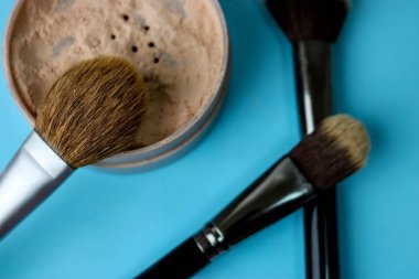 Güzellik kutusu, ufalanan mat mineral toz bir fırçayla özel kahverengi güzel ahşap doğal nap sıcak mavi arka plan üzerinde makyaj için gelen