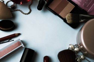 Çerçeve bir ruj, vurgulayıcı, dudaklar, fırça, fırçalar, parfüm, pudra, için bir kalem kadın kozmetik bir dizi mavi bir arka plan üzerinde süsler. Güzellik kutusunu düz yatıyordu. Üstten görünüm