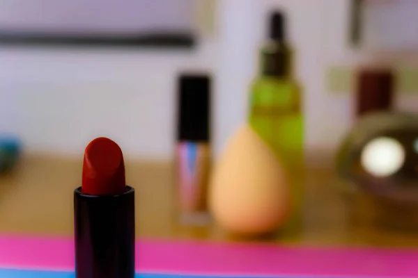 Rojo lipad de moda de los labios, y resaltador en el fondo de una mesa de maquillaje de belleza — Foto de Stock