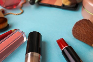 Çerçeve bir ruj, vurgulayıcı, dudaklar, fırça, fırçalar, parfüm, pudra, için bir kalem kadın kozmetik bir dizi mavi bir arka plan üzerinde süsler. Güzellik kutusunu düz yatıyordu. Üstten görünüm