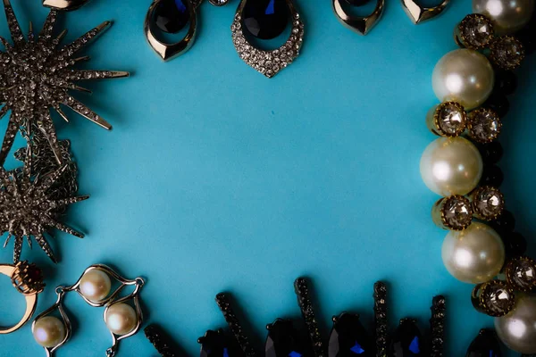 Красивые драгоценные блестящие ювелирные изделия модный гламурный набор ювелирных изделий, ожерелье, серьги, кольца, цепи, броши с жемчугом и бриллиантами на синем фоне. Плоская кладка, вид сверху, копирующее место — стоковое фото