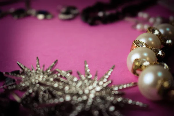 Beaux bijoux brillants précieux bijoux glamour tendance serti, collier, boucles d'oreilles, bagues, chaînes, broches avec des perles et des diamants sur un fond violet rose. Pose plate, vue du dessus, endroit de copie — Photo