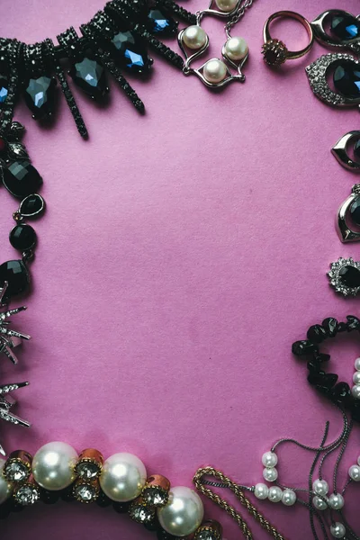 Красивые драгоценные блестящие ювелирные изделия модный гламурный набор ювелирных изделий, ожерелье, серьги, кольца, цепи, броши с жемчугом и бриллиантами на розовом фиолетовом фоне. Плоская кладка, вид сверху, копирующее место — стоковое фото
