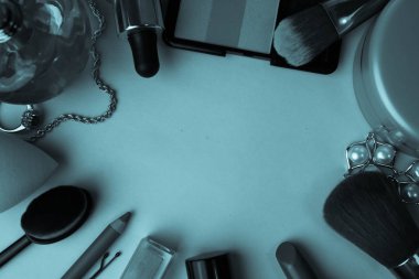 Çerçeve bir ruj, vurgulayıcı, dudaklar, fırça, fırçalar, parfüm, pudra, için bir kalem kadın kozmetik bir dizi mavi bir arka plan üzerinde süsler. Güzellik kutusunu düz yatıyordu. Üstten görünüm