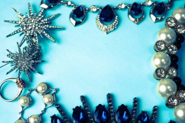 Güzel değerli parlak takı modaya uygun göz alıcı takı set, kolye, küpe, yüzük, zincirler, inci ve mavi bir arka plan üzerinde elmas broş. Düz yatıyordu, en iyi görünüm, kopya yer